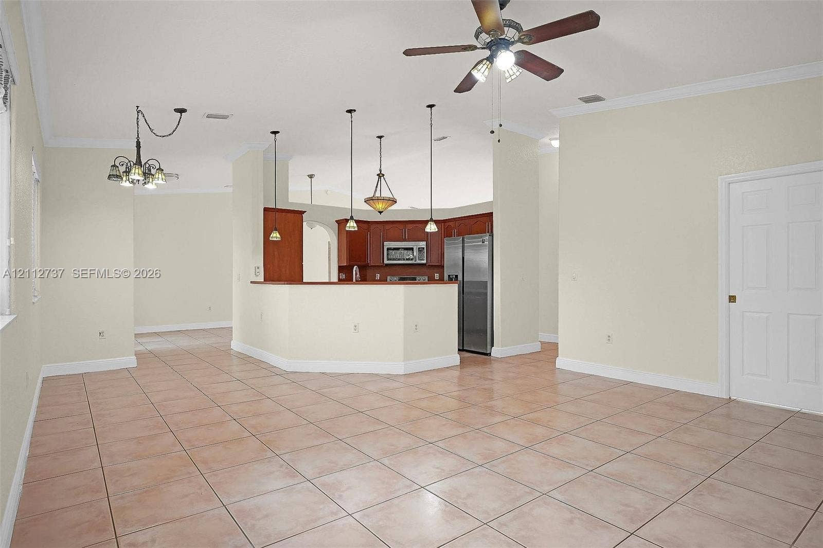 27902 SW 159th Court, Homestead, FL 33031 Open-concept interior featuring ceramic tile flooring, tray ceilings, dark-finish cabinetry, built-in stainless steel appliances, and multi-light hanging fixtures