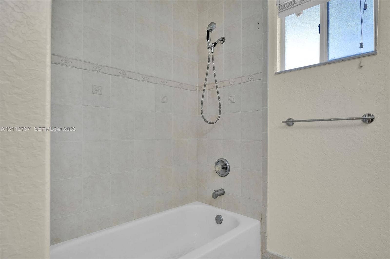 27902 SW 159th Court, Homestead, FL 33031 Bathtub and shower combination featuring neutral ceramic wall tile, a handheld showerhead, a chrome faucet assembly, and an integrated towel bar