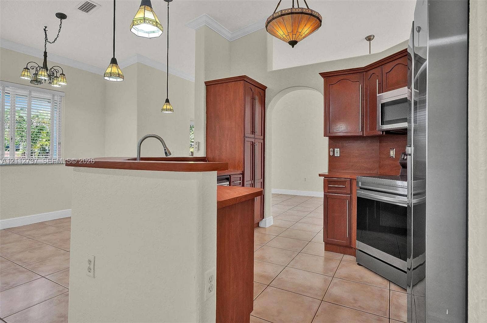 27902 SW 159th Court, Homestead, FL 33031 Kitchen featuring wood cabinetry, stainless steel appliances, tile flooring, and multi-light pendant fixtures