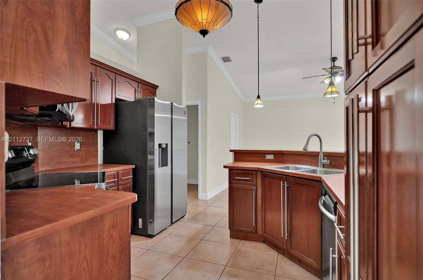 27902 SW 159th Court, Homestead, FL 33031 Kitchen featuring cherry-finish cabinetry, stainless steel appliances, ceramic tile flooring, vaulted ceilings, and decorative pendant lighting
