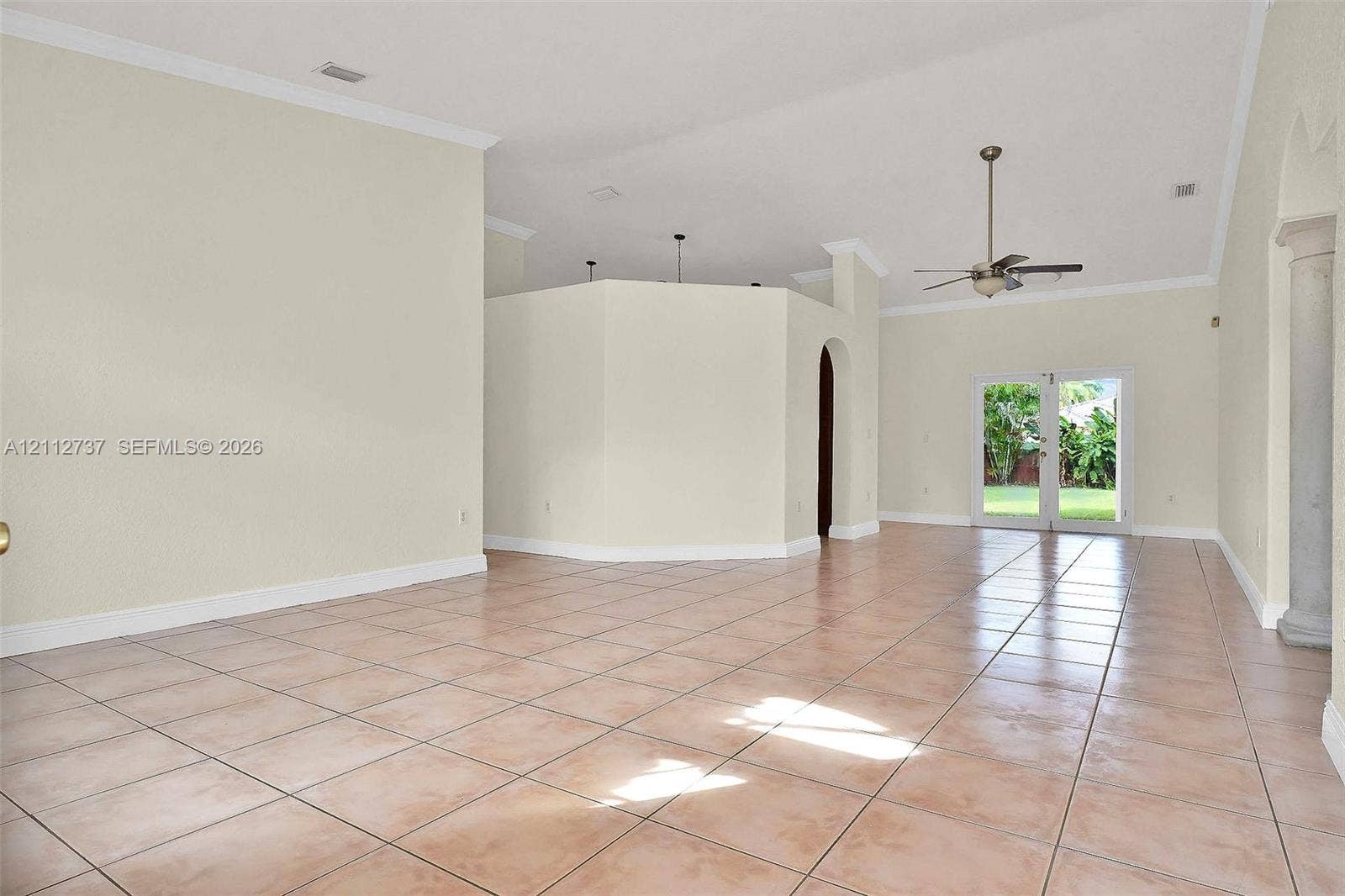 27902 SW 159th Court, Homestead, FL 33031 Open-concept interior featuring vaulted ceilings, ceramic tile flooring, a decorative column, and dual glass-paned doors