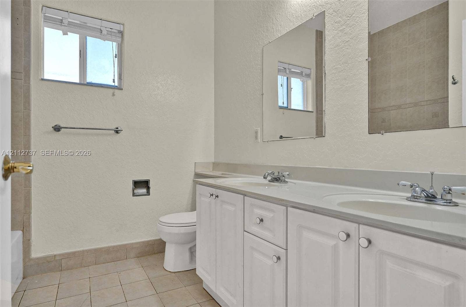 27902 SW 159th Court, Homestead, FL 33031 Dual-sink vanity with white cabinetry, light-toned countertop, and rectangular wall-mounted mirrors, complemented by tile flooring