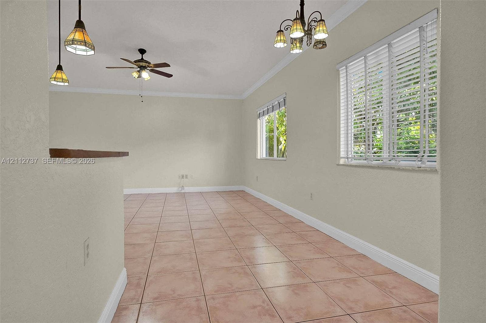 27902 SW 159th Court, Homestead, FL 33031 Interior space featuring tile flooring, crown molding, a multi-light chandelier, a ceiling fan with integrated lighting, and dual pendant lights over a pass-through opening