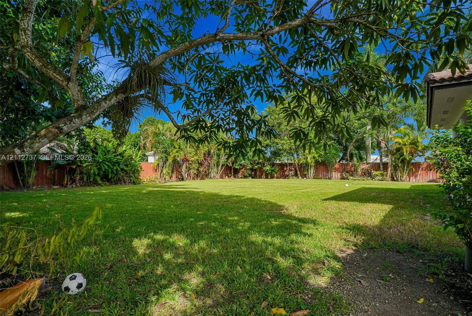 27902 SW 159th Court, Homestead, FL 33031 Expansive backyard featuring a manicured lawn, mature trees, and perimeter wood fencing