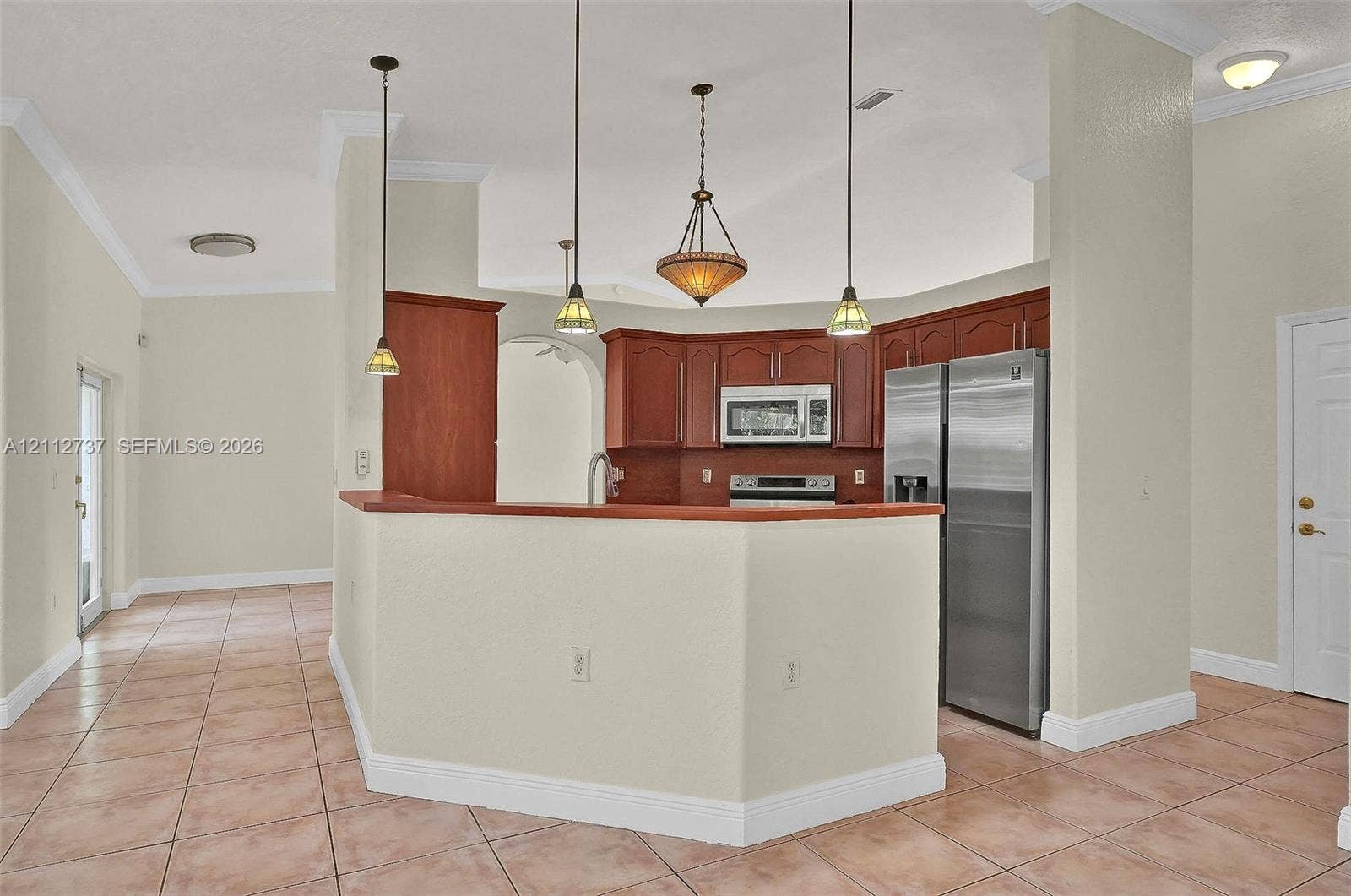 27902 SW 159th Court, Homestead, FL 33031 Kitchen featuring wood cabinetry, stainless steel appliances, tile flooring, crown molding, and pendant lighting