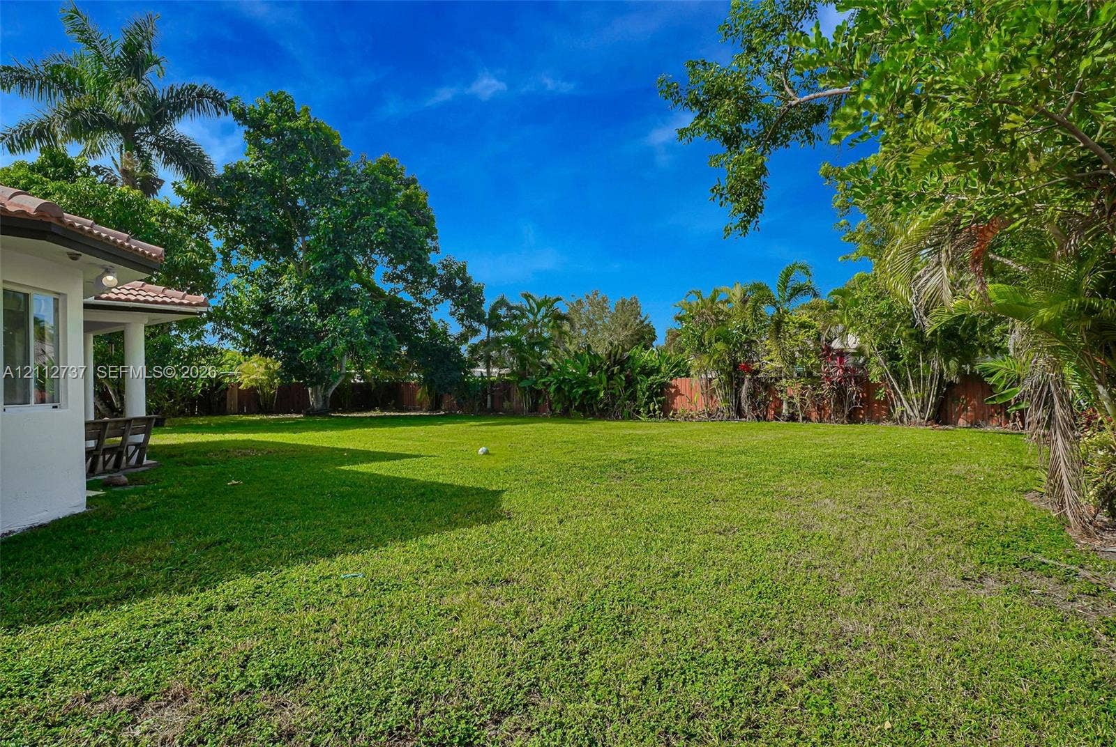 27902 SW 159th Court, Homestead, FL 33031 Expansive backyard featuring a large grass lawn, perimeter wood fencing, and mature tropical landscaping
