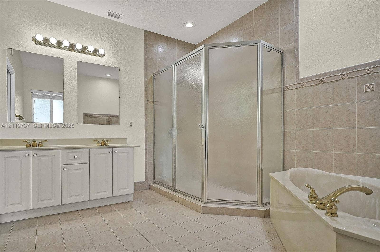 27902 SW 159th Court, Homestead, FL 33031 Dual vanity with white cabinetry, corner shower enclosure with glass panels, separate soaking tub, and tile flooring