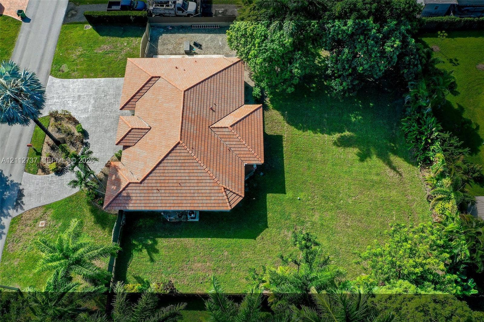 27902 SW 159th Court, Homestead, FL 33031 Aerial perspective featuring a tile roof, expansive grass lawn, paved driveway, and mature landscaping