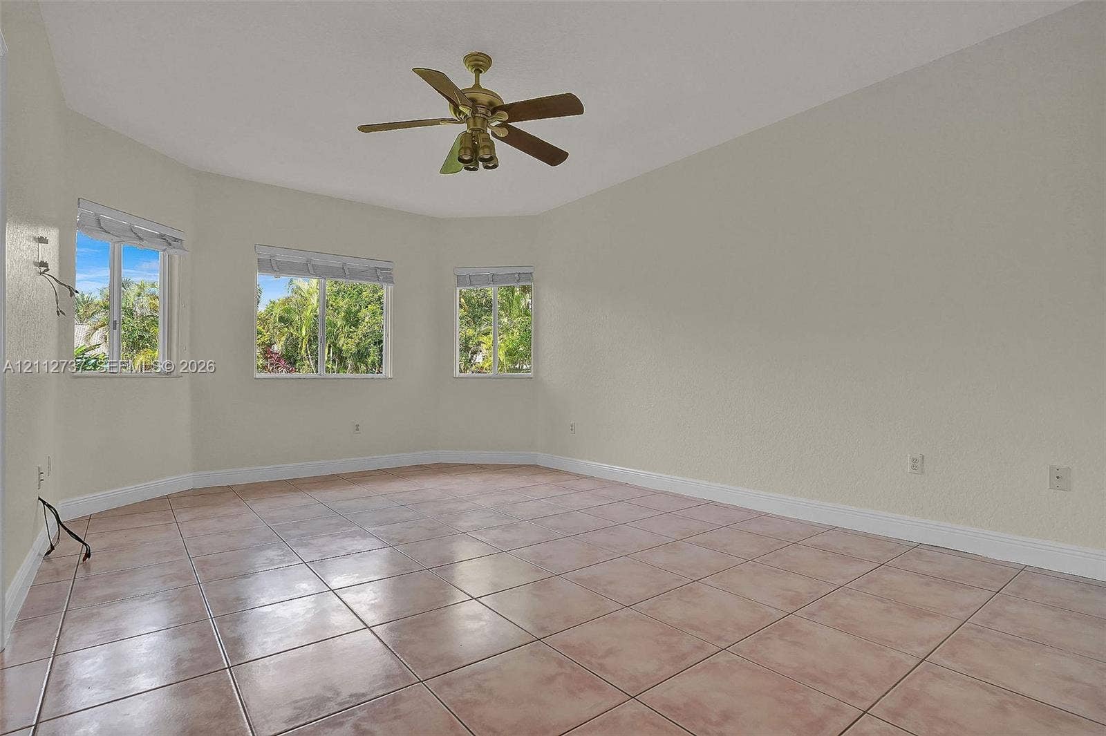 27902 SW 159th Court, Homestead, FL 33031 Spacious room featuring neutral wall tones, ceramic tile flooring, three large windows, and a multi-blade ceiling fan with integrated lighting