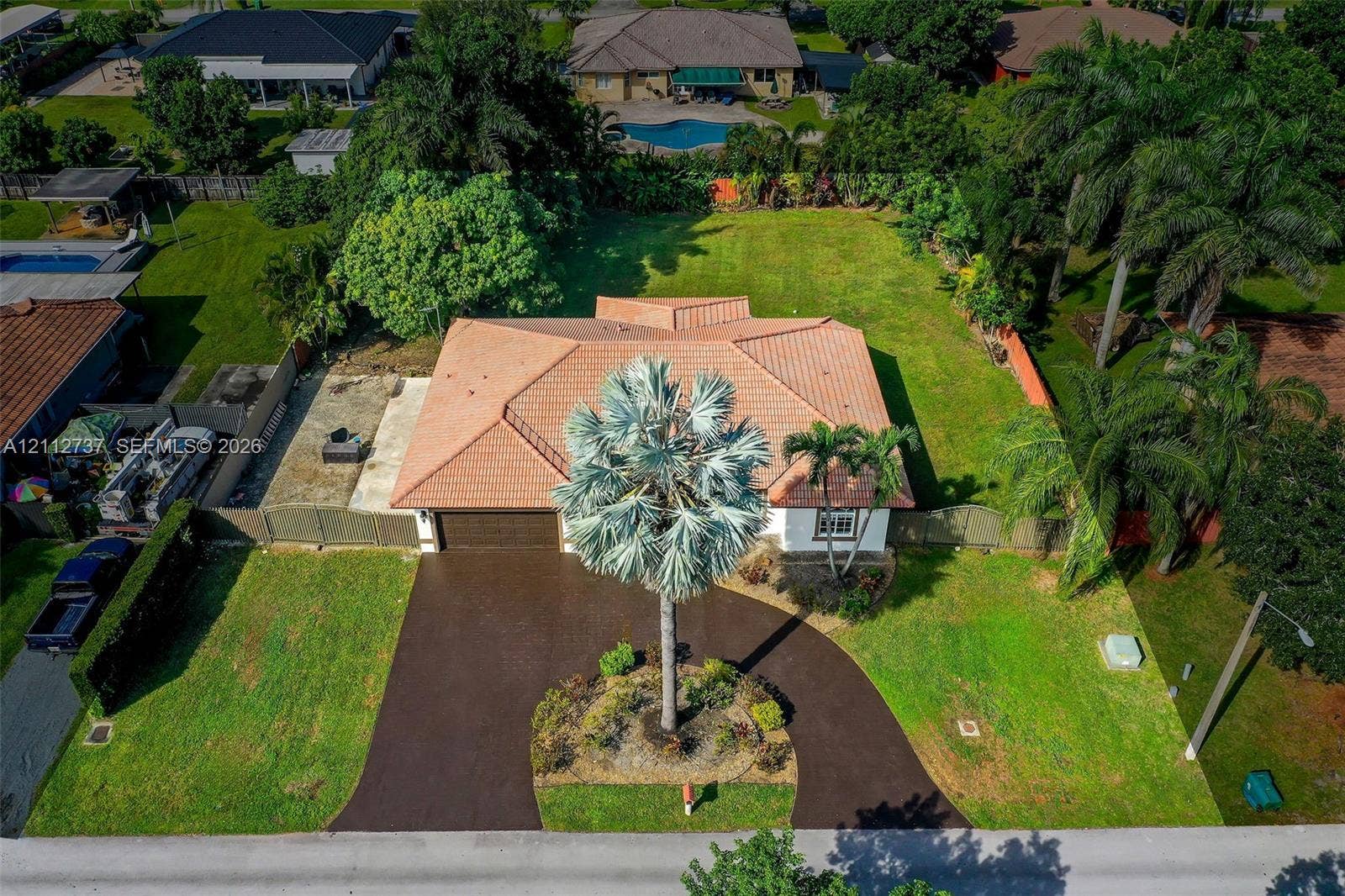27902 SW 159th Court, Homestead, FL 33031 Aerial perspective of a property featuring a multi-hipped tile roof, a circular asphalt driveway, and expansive lawn space
