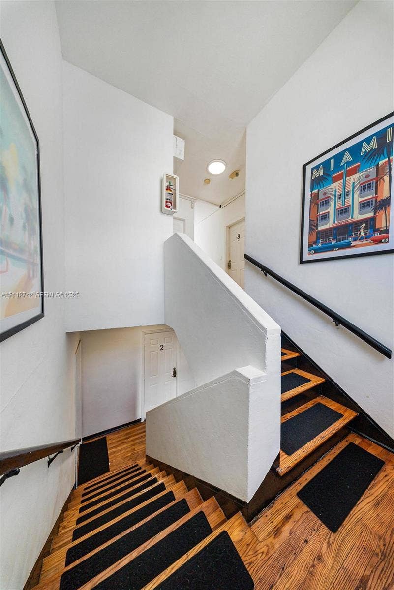 7124 Bay Drive, Miami Beach, FL 33141 Stairwell featuring wood-finish treads, matte black handrails, and flush-mount ceiling lighting