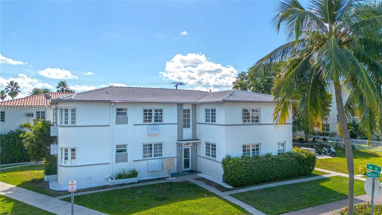 7124 Bay Drive, Miami Beach, FL 33141 Two-story stucco exterior featuring a hipped tile roof, multi-pane windows, and corner architectural detailing