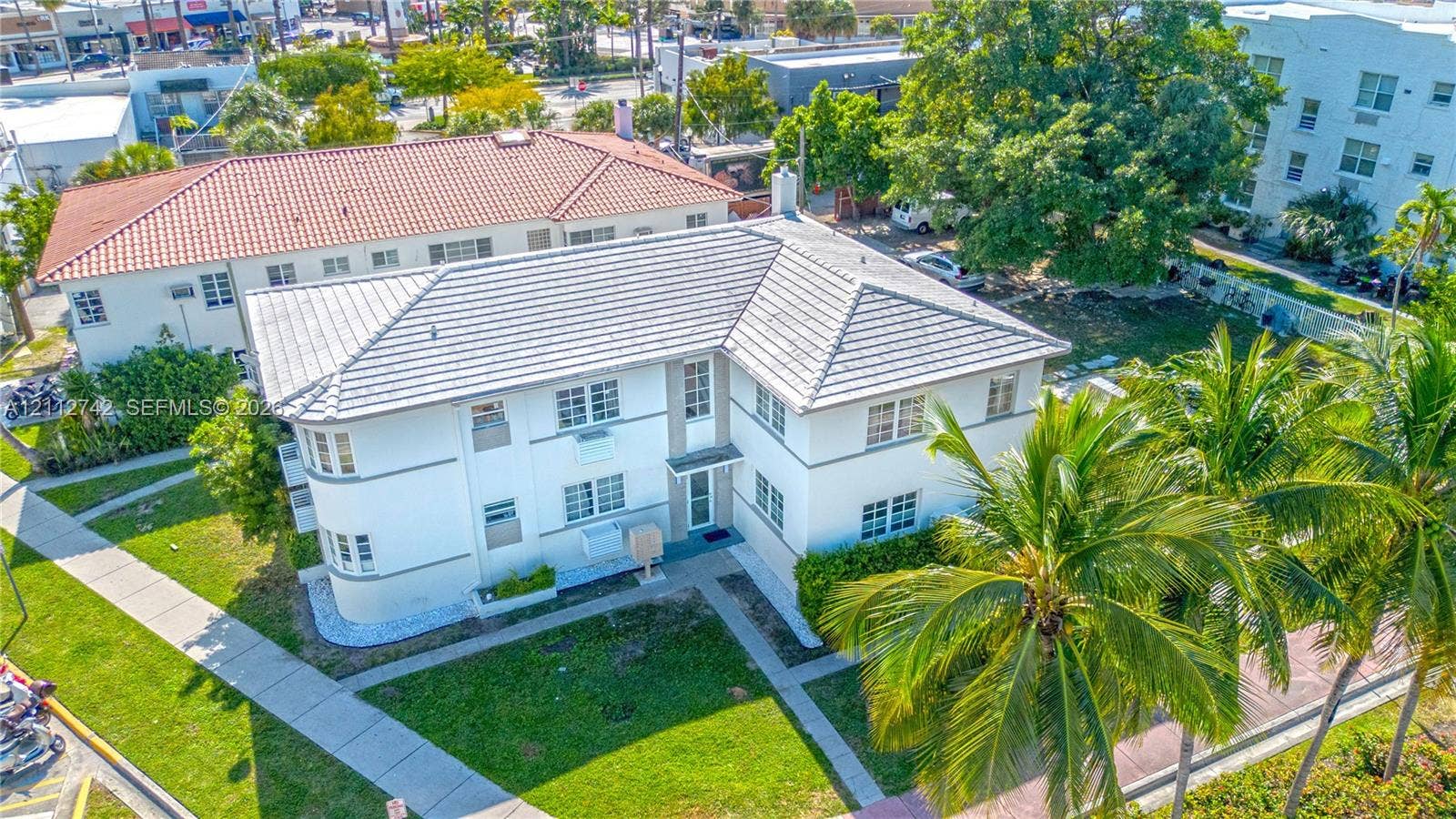 7124 Bay Drive, Miami Beach, FL 33141 Multi-level building featuring a light-colored stucco exterior, a hipped roof with light-toned tiles, and rounded architectural wall detailing