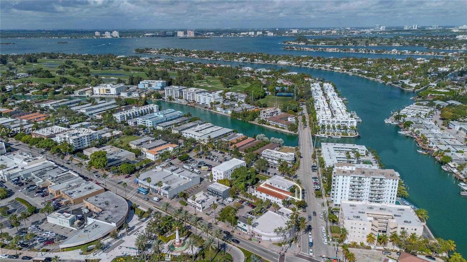 7124 Bay Drive, Miami Beach, FL 33141 Aerial perspective of a multi-story property featuring a terra-cotta tile roof, perimeter landscaping, and a corner lot configuration within a coastal waterway district