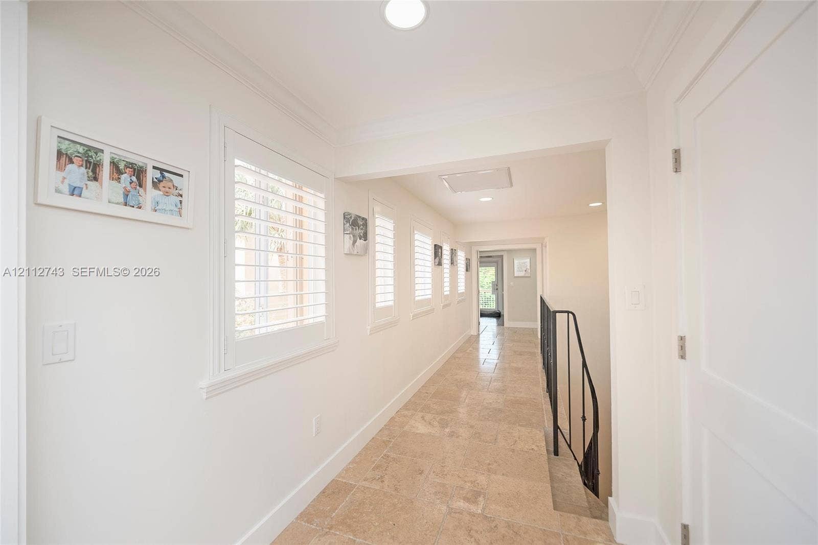 6157 Paradise Point Drive, Palmetto Bay, FL 33157 Hallway featuring stone tile flooring, plantation shutters, recessed lighting, and crown molding