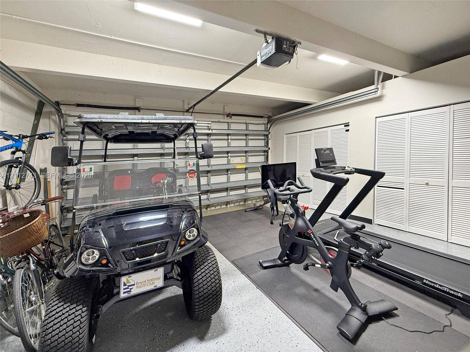 6157 Paradise Point Drive, Palmetto Bay, FL 33157 Multi-car garage featuring epoxy-coated flooring, built-in wall shelving, and dual sets of louvered-door closets
