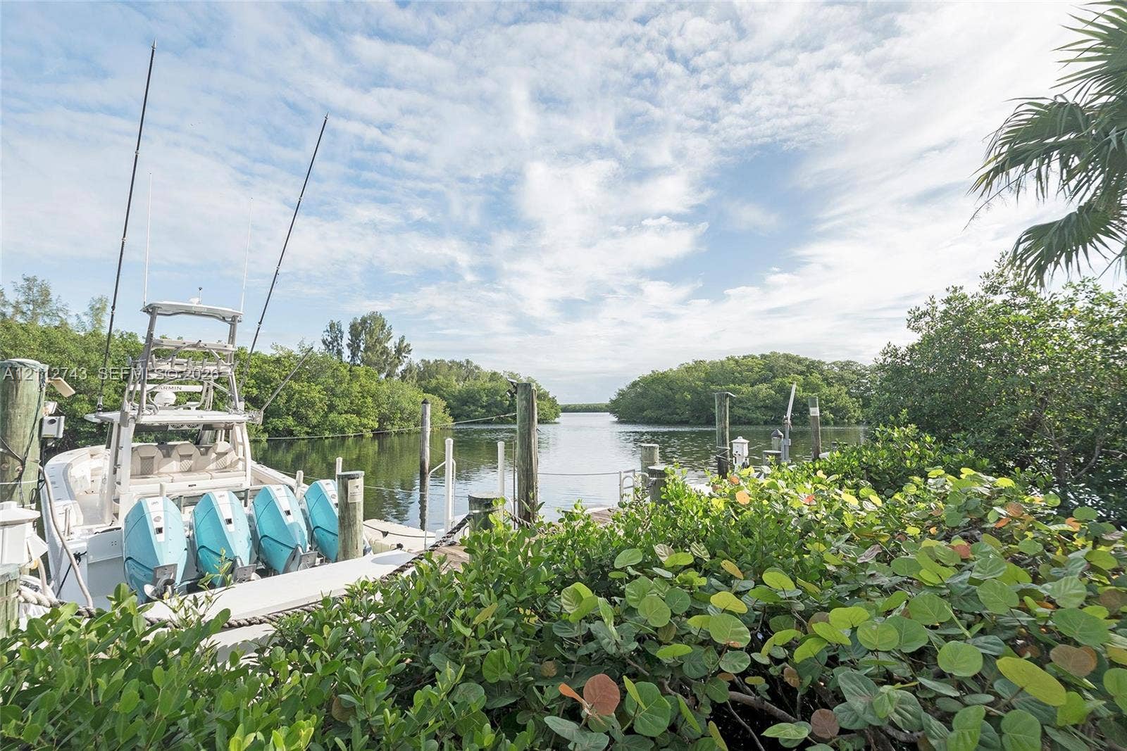 6157 Paradise Point Drive, Palmetto Bay, FL 33157 Waterfront property featuring a private boat dock, wooden pilings, and dense coastal vegetation