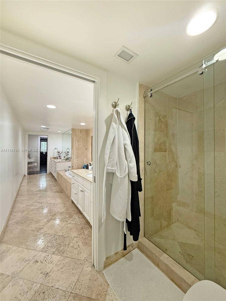 6157 Paradise Point Drive, Palmetto Bay, FL 33157 Bathroom featuring large-format tile flooring, a glass-enclosed shower with stone tile surround, and built-in cabinetry with a stone countertop