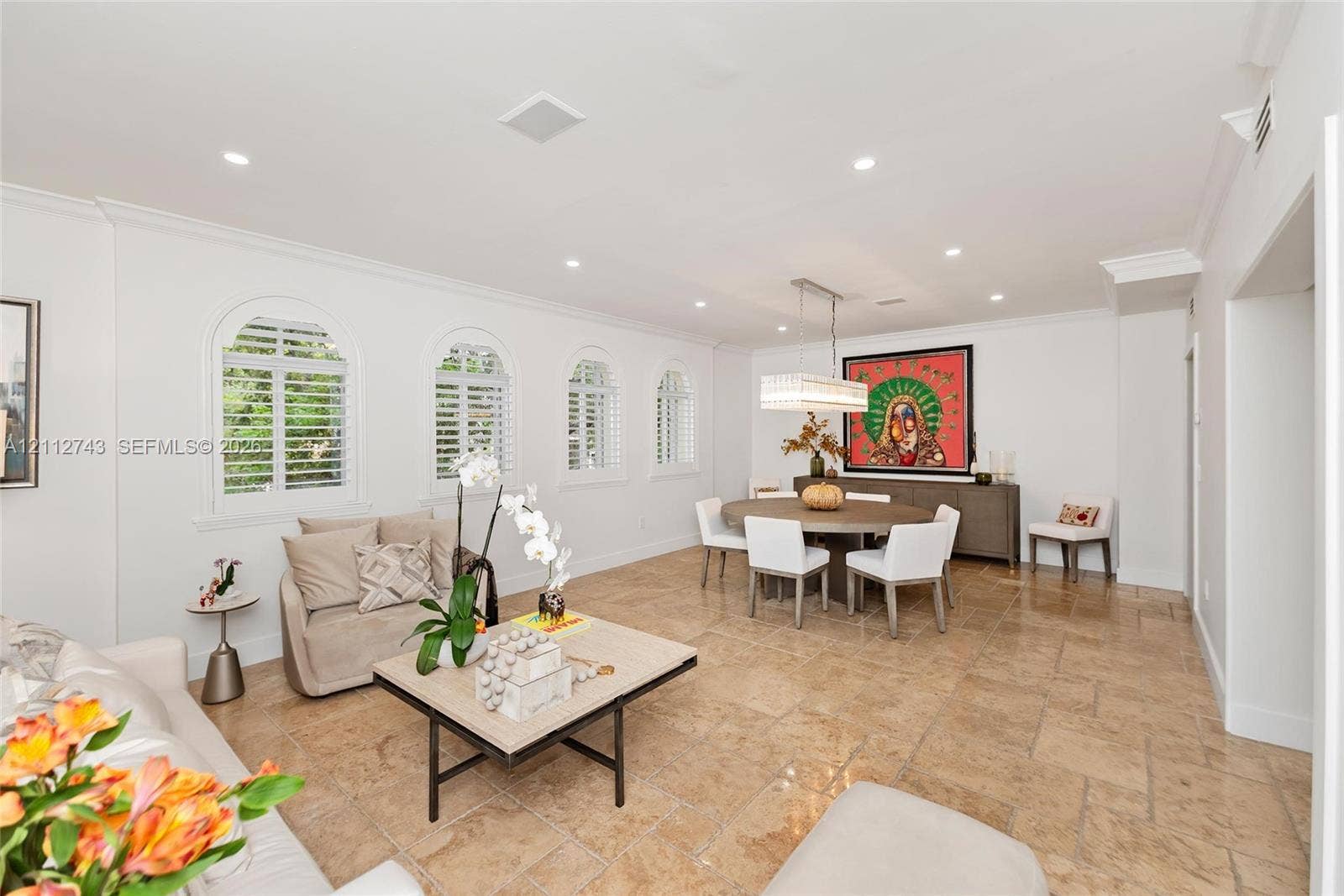 6157 Paradise Point Drive, Palmetto Bay, FL 33157 Open-concept space featuring stone tile flooring, crown molding, recessed lighting, and four arched windows with shutter treatments
