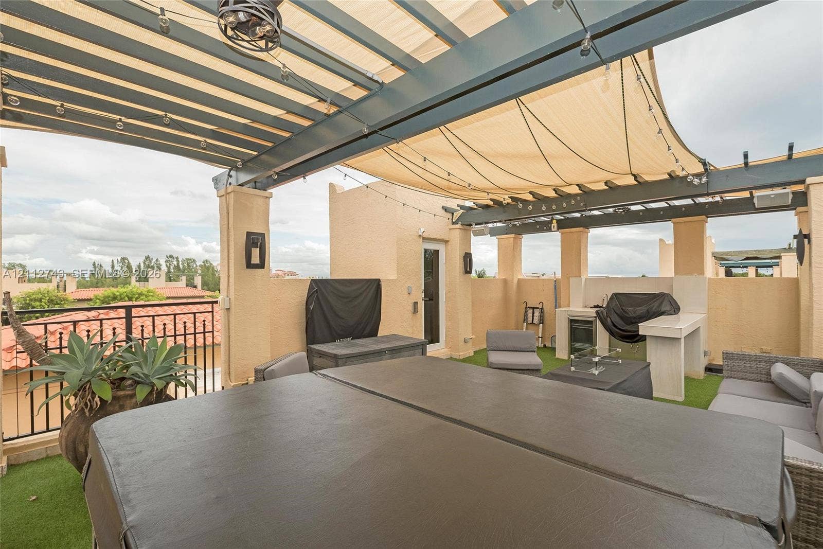 6157 Paradise Point Drive, Palmetto Bay, FL 33157 Rooftop terrace featuring a covered pergola with a retractable shade canopy, built-in outdoor kitchen, integrated lighting, and artificial turf flooring