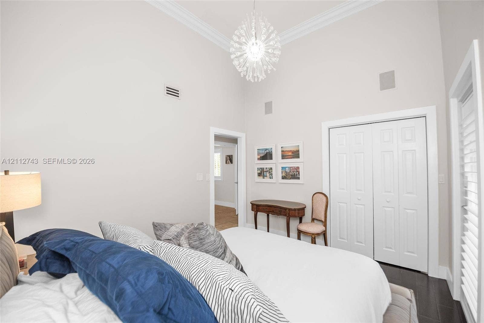 6157 Paradise Point Drive, Palmetto Bay, FL 33157 High ceilings featuring crown molding, a decorative crystal-style chandelier, double-panel closet doors, and plantation shutters