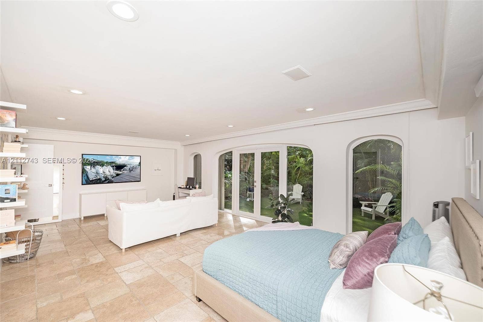 6157 Paradise Point Drive, Palmetto Bay, FL 33157 Spacious room featuring light-toned tile flooring, recessed lighting, built-in shelving, white French doors, and arched glass inserts