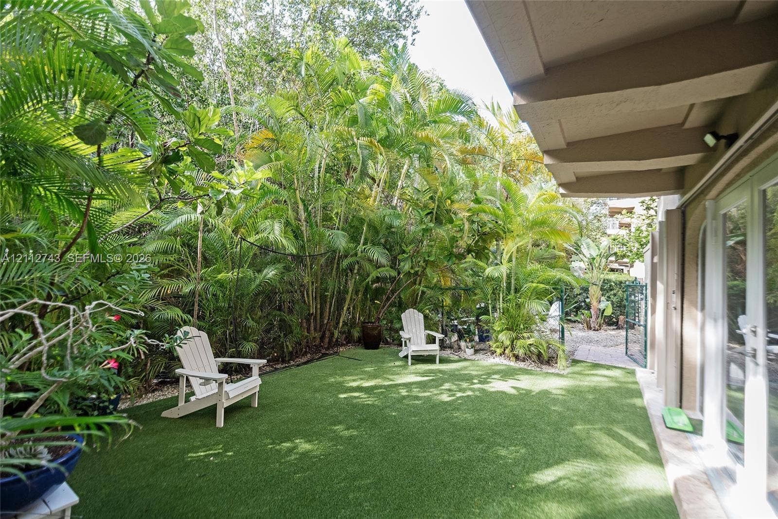 6157 Paradise Point Drive, Palmetto Bay, FL 33157 Private outdoor space featuring synthetic lawn, established tropical landscaping, and a covered patio