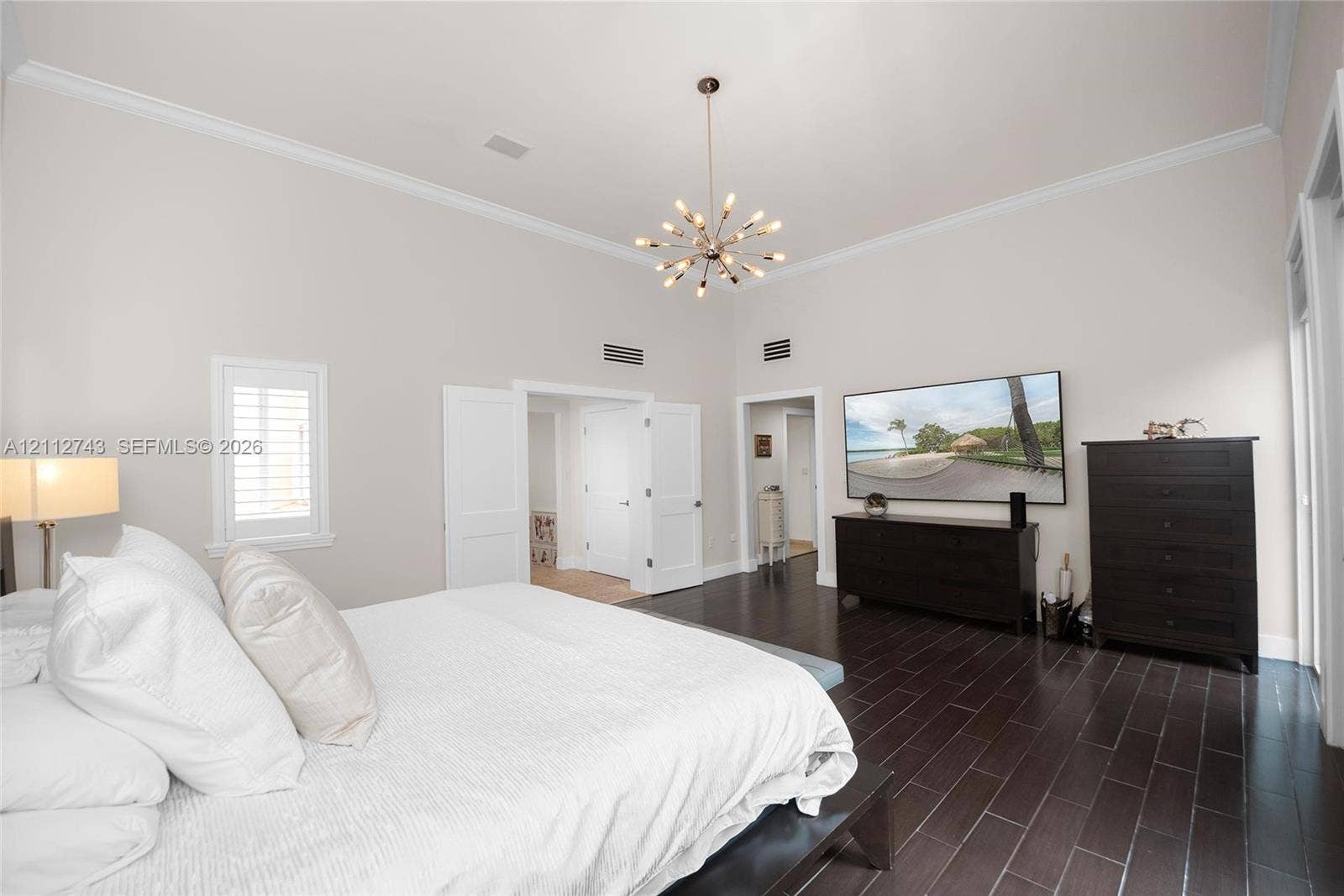 6157 Paradise Point Drive, Palmetto Bay, FL 33157 High ceilings featuring crown molding, dark wood-finish flooring, and a modern sputnik-style chandelier