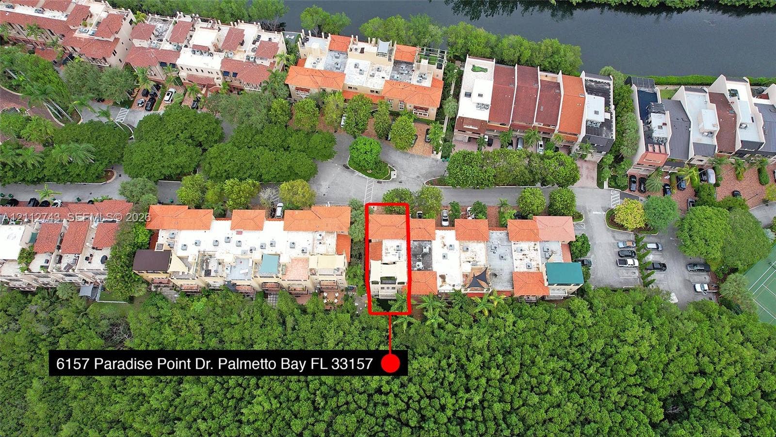 6157 Paradise Point Drive, Palmetto Bay, FL 33157 Aerial perspective of property featuring a multi-story structure with a terra cotta tile roof, positioned on a waterfront lot with dense perimeter landscaping