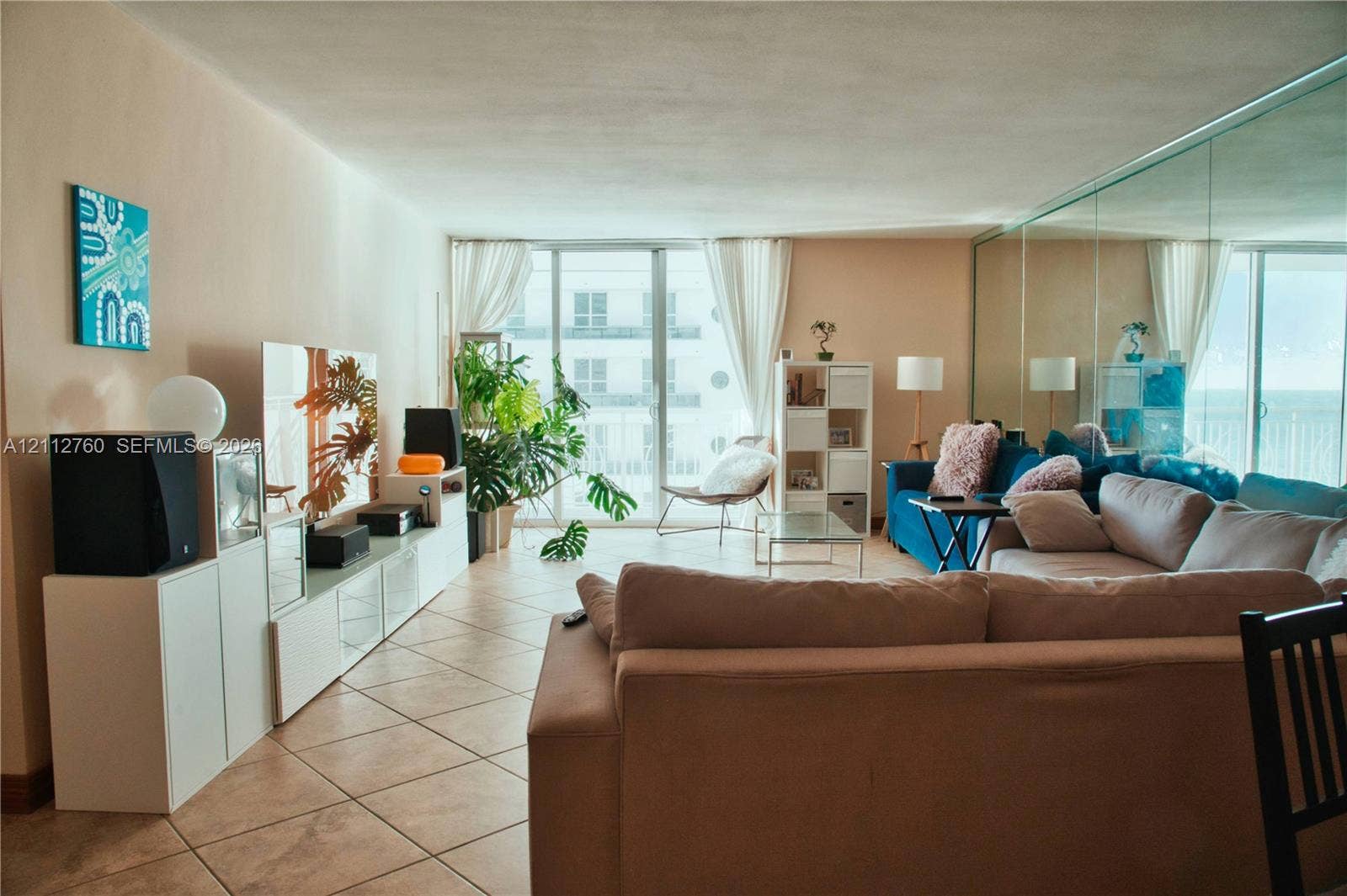 5825 Collins Avenue, #11H, Miami Beach, FL 33140 Ceramic tile flooring, full-wall mirrored accent, and sliding glass doors providing outdoor access