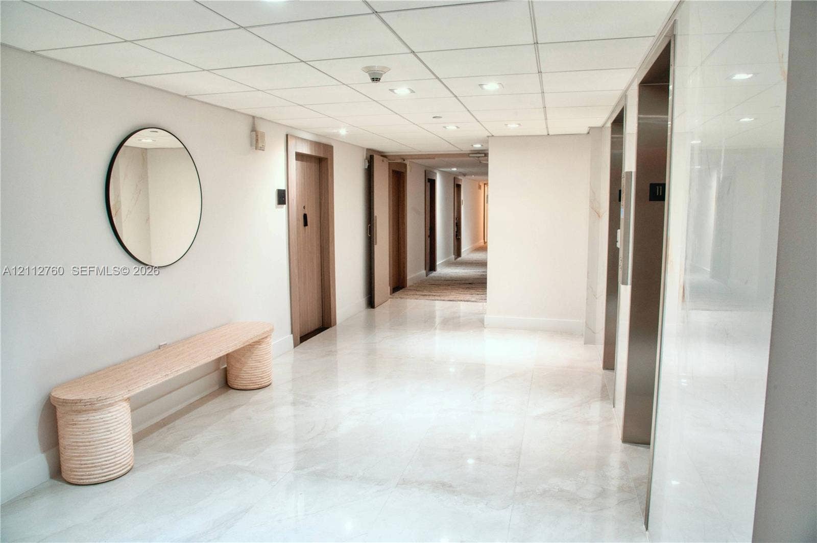5825 Collins Avenue, #11H, Miami Beach, FL 33140 Common area hallway featuring polished stone-finish flooring, recessed ceiling lighting, and stainless steel elevator doors