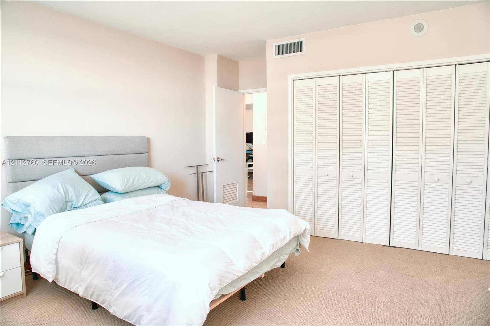 5825 Collins Avenue, #11H, Miami Beach, FL 33140 Wall-to-wall carpeting, expansive floor-to-ceiling closets with white louvered bi-fold doors, and neutral wall tones
