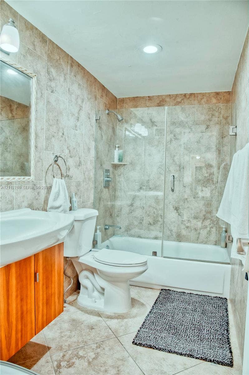 5825 Collins Avenue, #11H, Miami Beach, FL 33140 Full-wall tile surround, glass shower enclosure, wood-finish vanity cabinet, and recessed ceiling lighting
