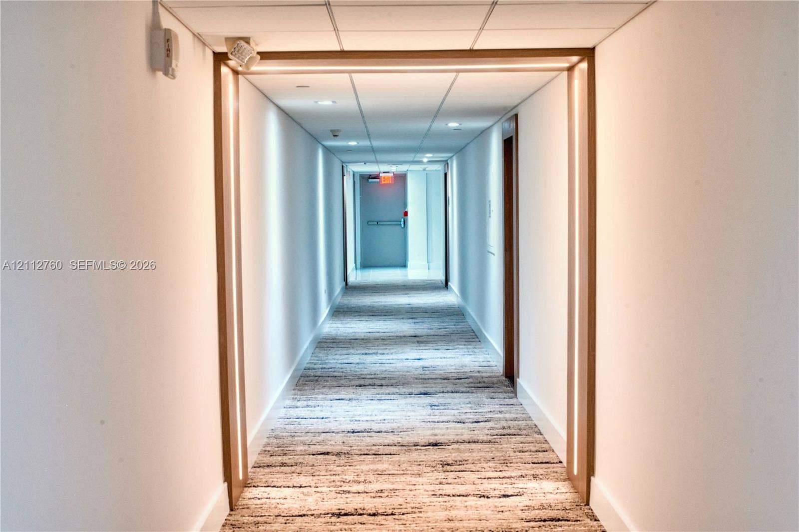 5825 Collins Avenue, #11H, Miami Beach, FL 33140 Hallway featuring integrated linear LED lighting, wood-trim portal framing, recessed ceiling lighting, and textured carpeting