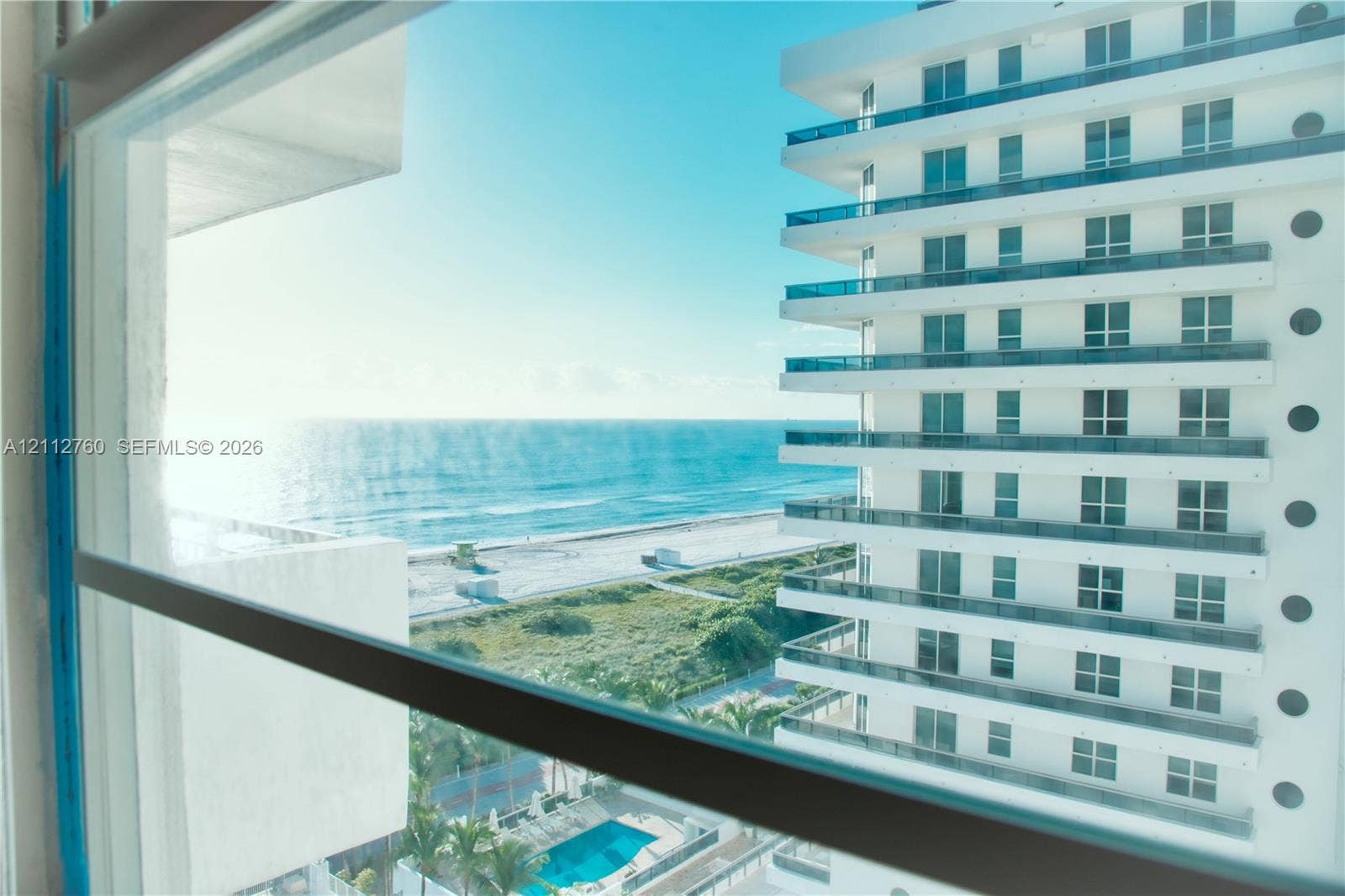 5825 Collins Avenue, #11H, Miami Beach, FL 33140 Multi-story white facade high-rise featuring stacked balconies with glass railings, an outdoor swimming pool, and coastal proximity