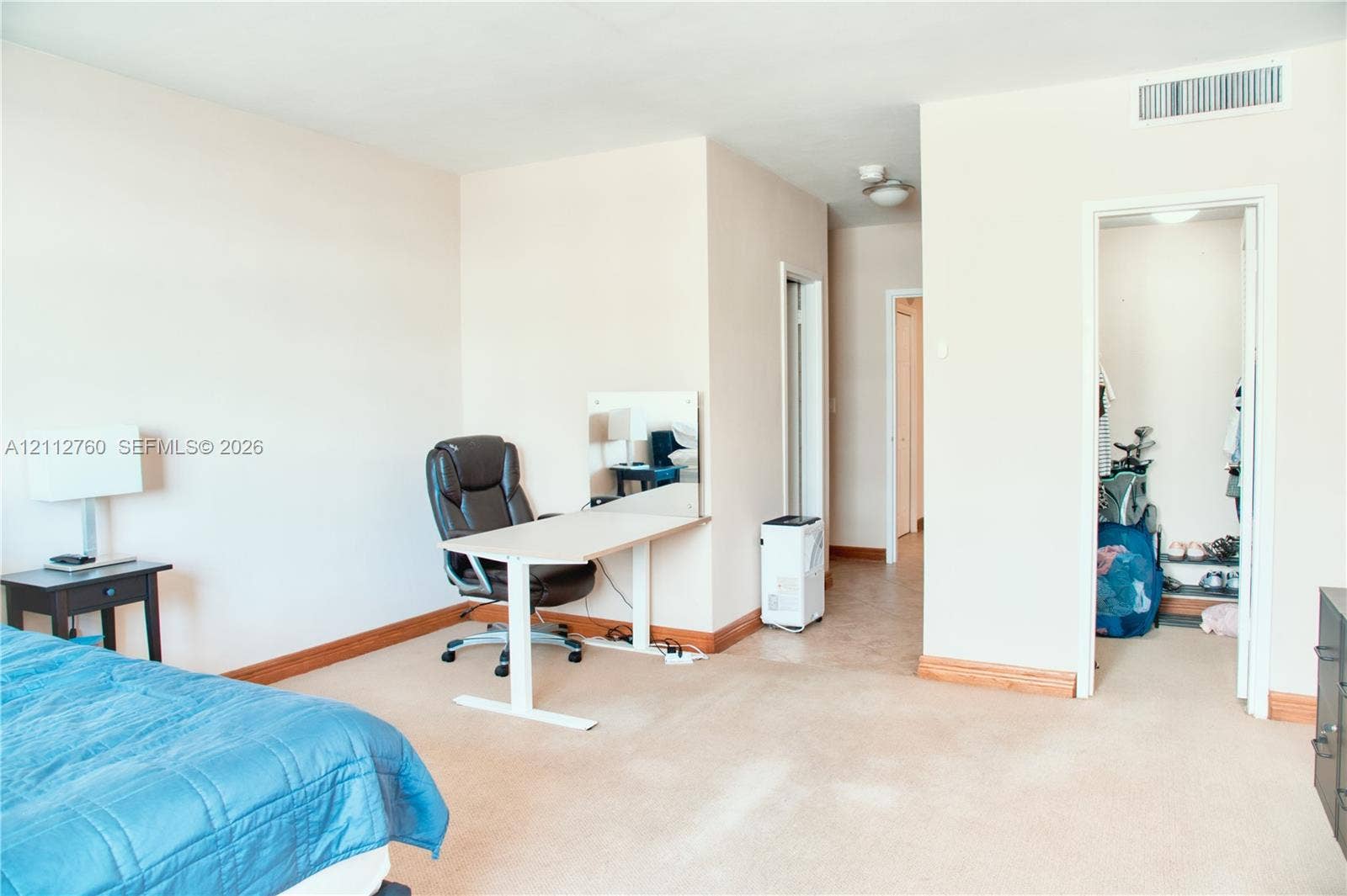 5825 Collins Avenue, #11H, Miami Beach, FL 33140 Neutral-toned interior space with wall-to-wall carpeting, wood trim, and a walk-in closet