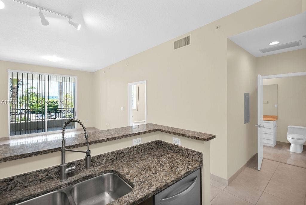 550 Okeechobee Boulevard, #224, West Palm Beach, West Palm Beach, FL 33401 Kitchen featuring a stone-surface breakfast bar, stainless steel double-basin sink, high-arc pull-down faucet, and tiled flooring