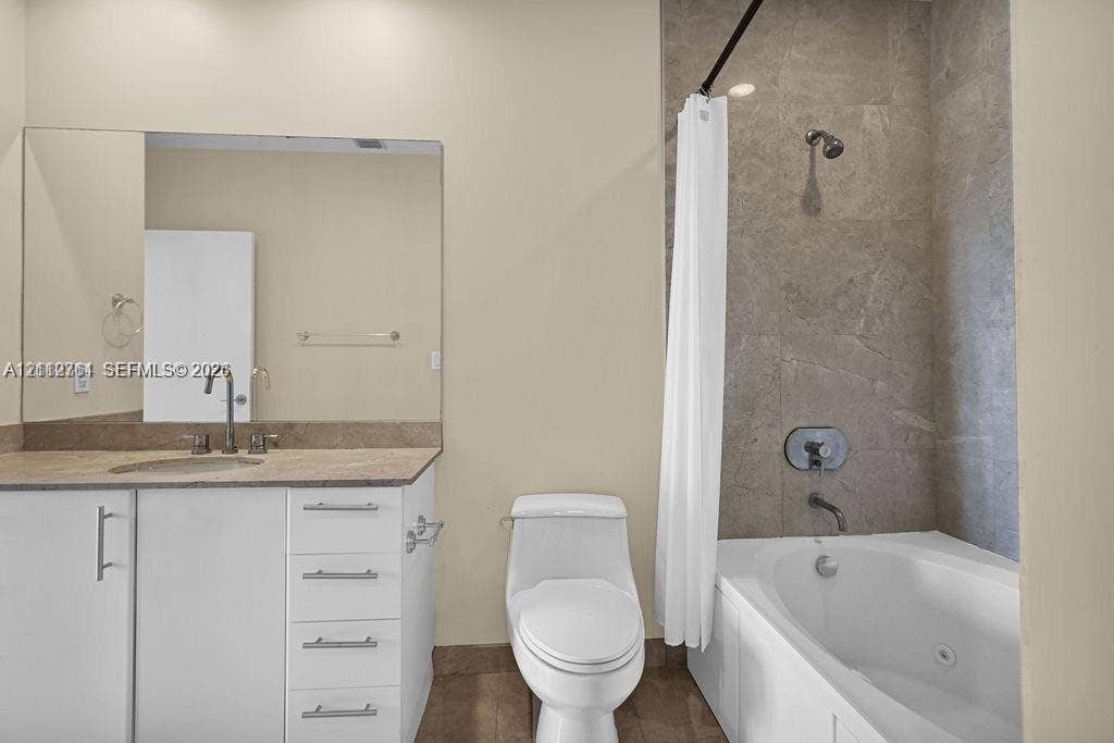 550 Okeechobee Boulevard, #224, West Palm Beach, West Palm Beach, FL 33401 Bathroom featuring a white vanity cabinet with stone-surfaced countertop, integrated undermount sink, large wall-mounted mirror, and a tub with a stone-tiled surround and stainless steel fixtures