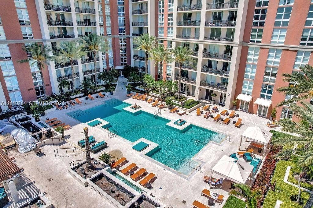 550 Okeechobee Boulevard, #224, West Palm Beach, West Palm Beach, FL 33401 Outdoor swimming pool featuring built-in sun shelves, expansive paved deck, multiple cabanas, and mature palm tree landscaping