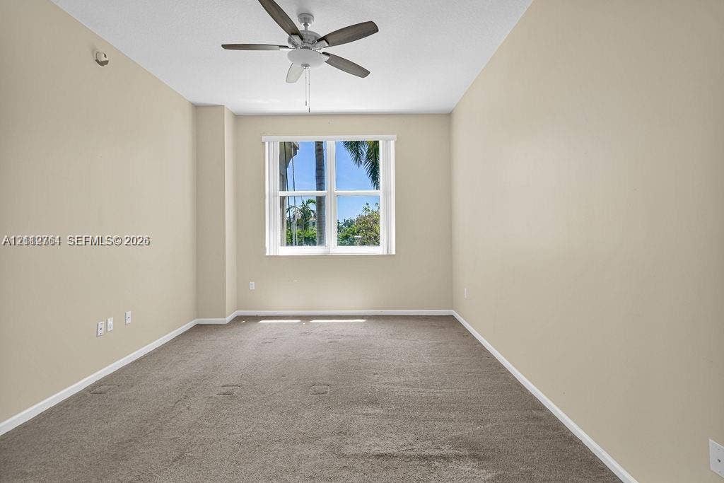 550 Okeechobee Boulevard, #224, West Palm Beach, West Palm Beach, FL 33401 Room featuring neutral-toned carpeting, a multi-blade ceiling fan with integrated lighting, and a dual-pane window