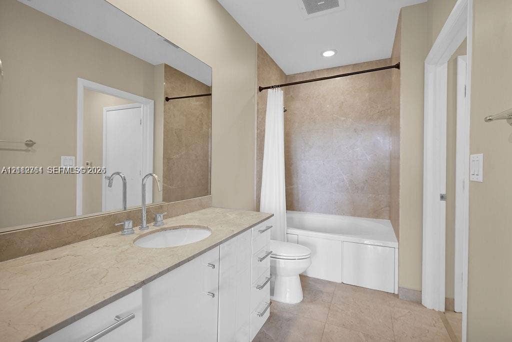 550 Okeechobee Boulevard, #224, West Palm Beach, West Palm Beach, FL 33401 Bathroom featuring a full-width wall mirror, white cabinetry with a stone-surface countertop, an integrated oval sink, and a shower-tub combination with large-format tile surround