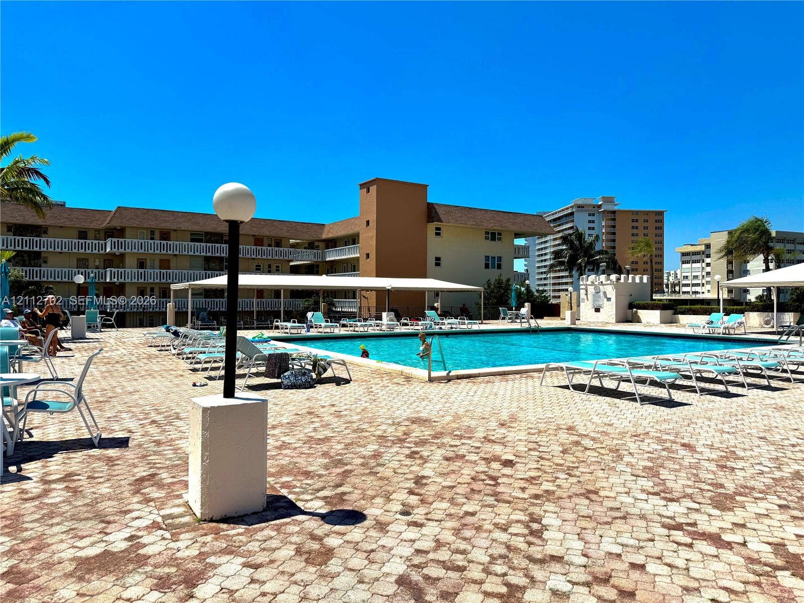 Outdoor swimming pool featuring a paved stone deck and a covered patio area