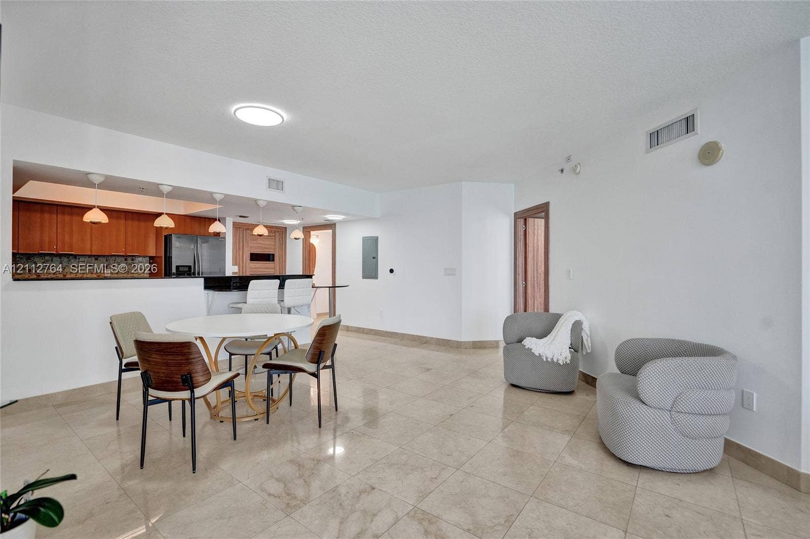 Open-concept area featuring tile flooring, kitchen with wood-finish cabinetry, breakfast bar, and recessed lighting