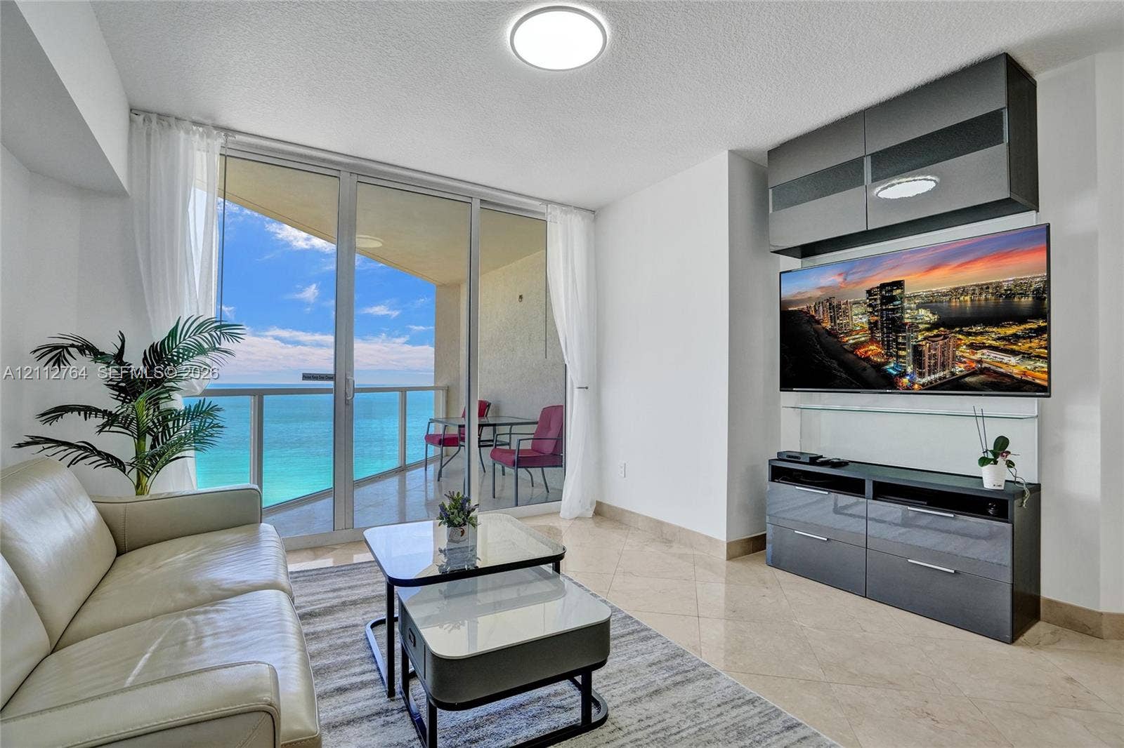 Floor-to-ceiling glass doors, expansive private balcony, polished stone flooring, and built-in high-gloss cabinetry