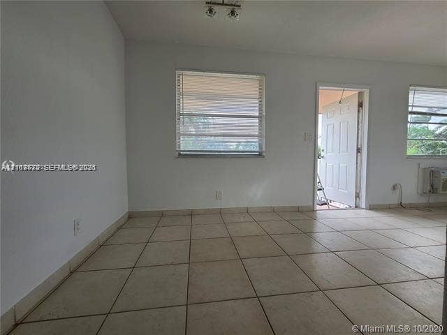 Interior space featuring ceramic tile flooring, neutral walls, multiple louvered windows, and a panelled exterior door