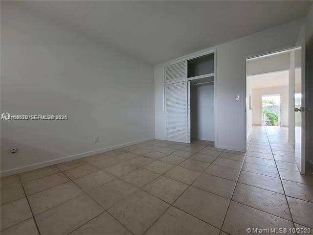 Neutral-toned ceramic tile flooring and built-in closet with louvered doors