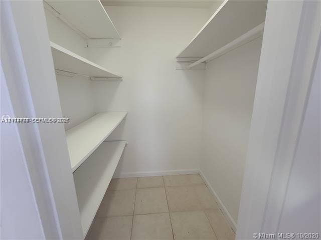 Walk-in storage space featuring ceramic tile flooring and tiered built-in shelving