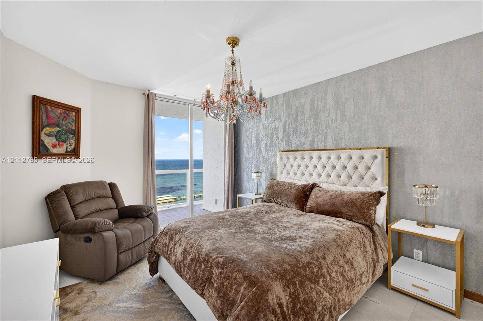 16425 Collins Avenue, #2016, Sunny Isles Beach, FL 33160 Floor-to-ceiling glass sliding doors with water scenery, intricate crystal chandelier, and textured accent wall