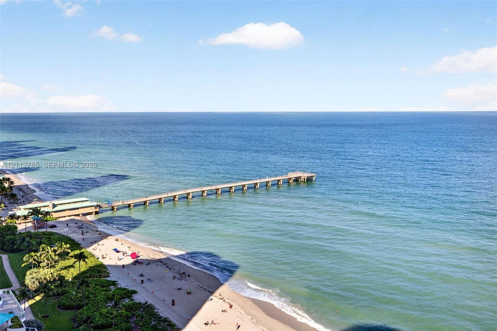 16425 Collins Avenue, #2016, Sunny Isles Beach, FL 33160 Oceanfront location featuring expansive sandy beach access, a long wooden pier, mature palm trees, and manicured green space