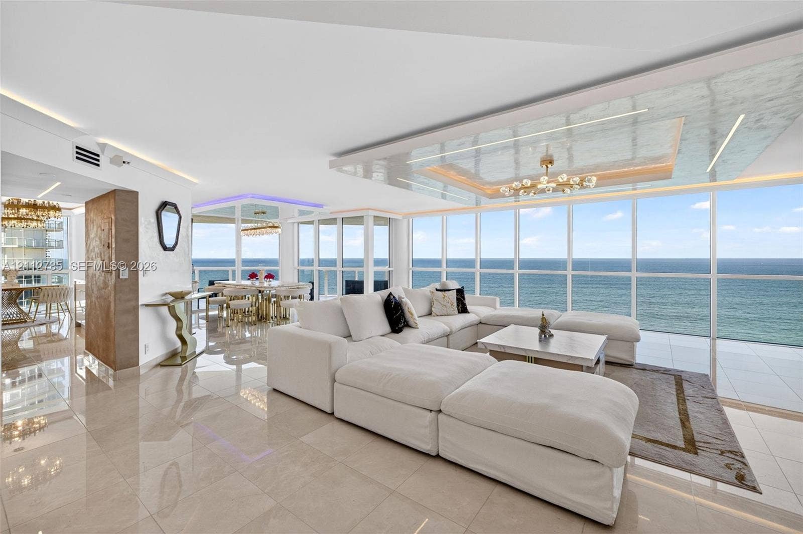16425 Collins Avenue, #2016, Sunny Isles Beach, FL 33160 Floor-to-ceiling windows featuring ocean horizon, recessed tray ceiling with integrated lighting, polished stone-finish flooring, and architectural metallic-finish wall paneling